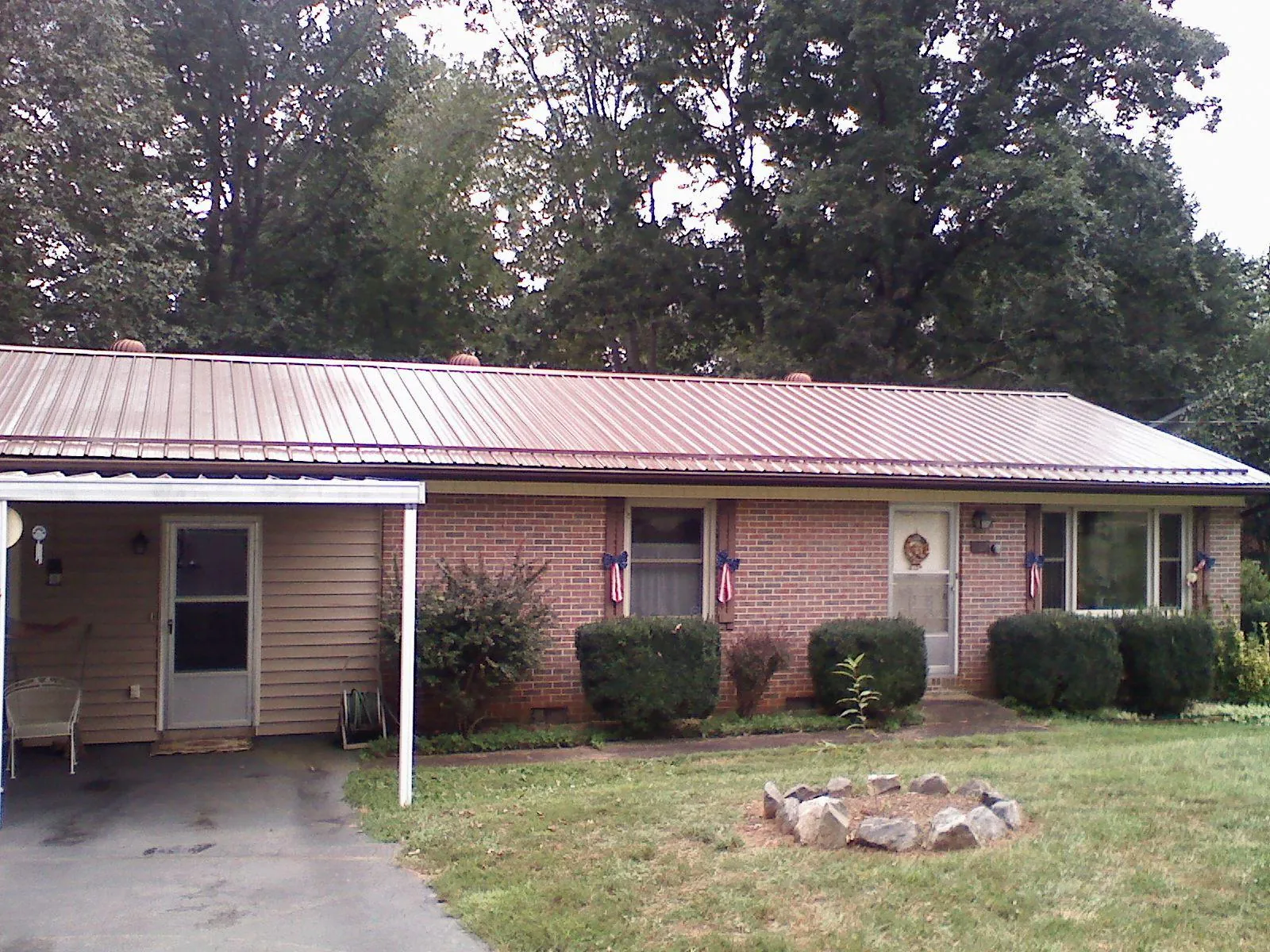 Bronze metal roof and carport on a brick ranch home — Roof Repair work by our crew in Derby